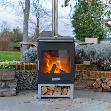 Une cheminée extérieure avec feu de bois sur une terrasse avec possibilité de stockage de bois sous la cheminée