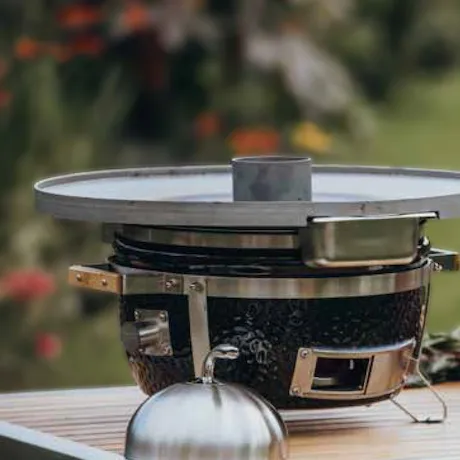 Eine Feuerplatte mit verschiedenen Grillzubehörteilen auf einem Tisch im Freien Eine Feuerplatte mit verschiedenen Grillzubehörteilen auf einem Tisch im Freien